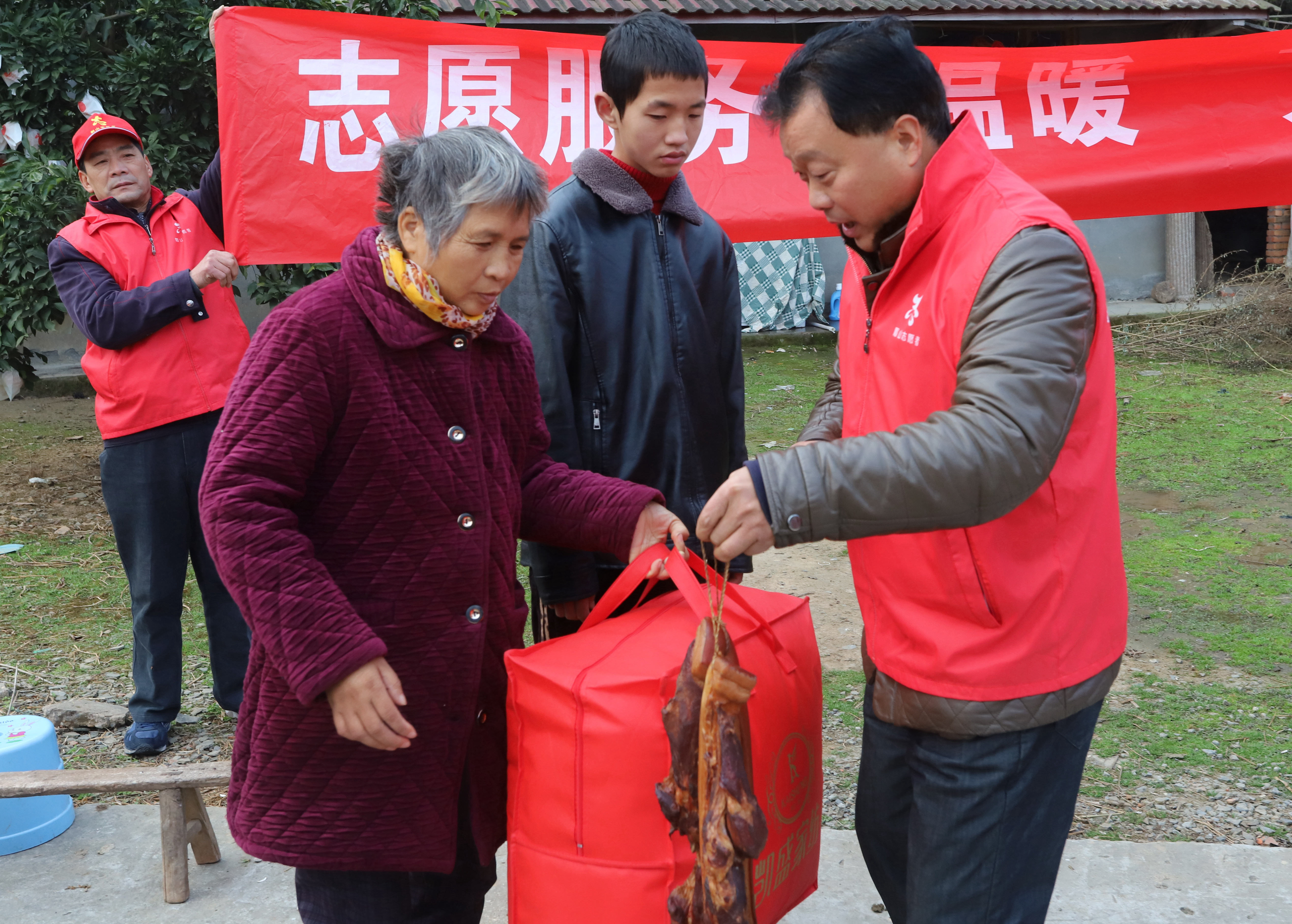 ２志愿者在为刘淑仙，张涛母子送被子和腊肉。.JPG