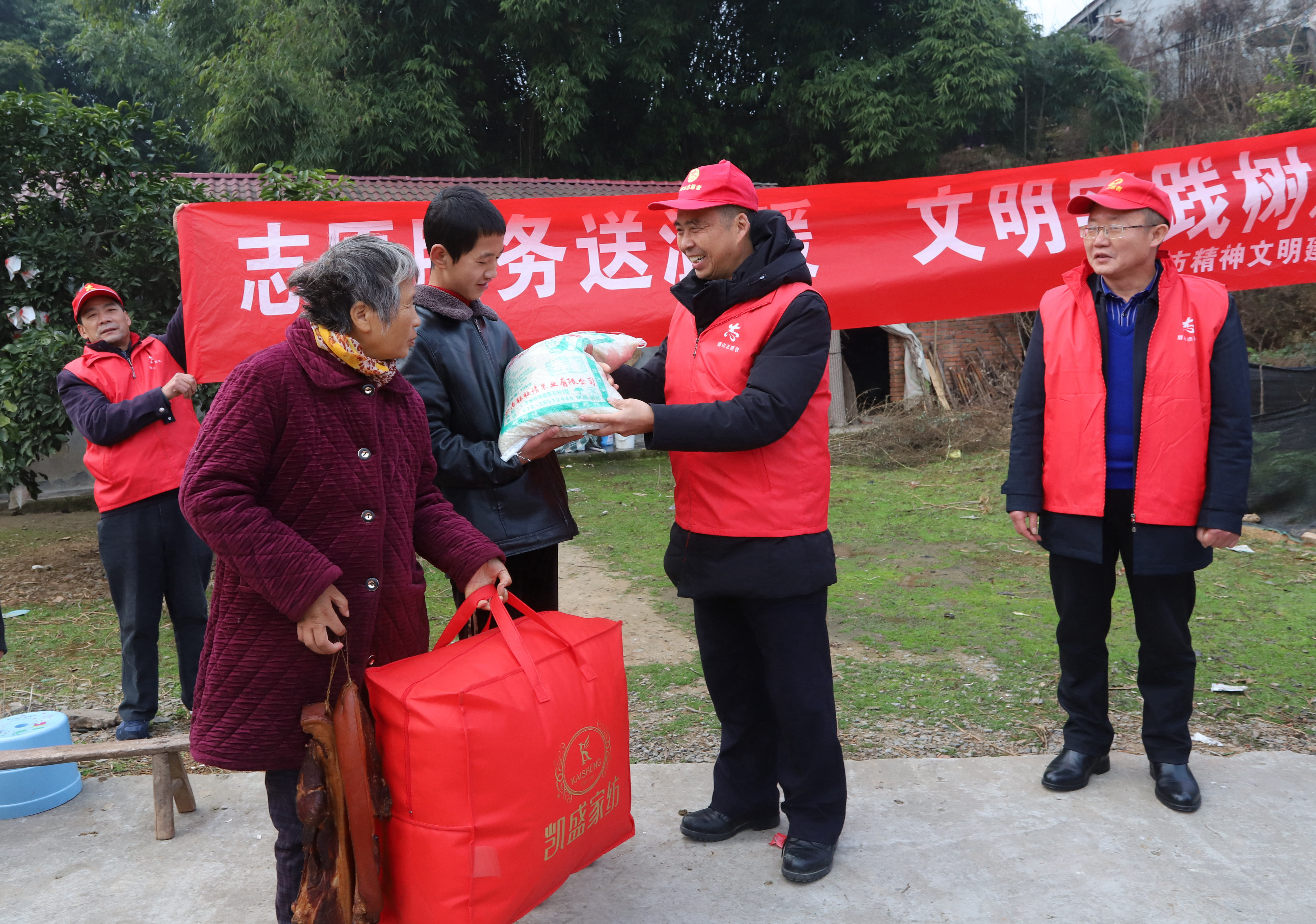 ４志愿者在为刘淑仙，张涛母子送被子，腊肉和大米。.JPG